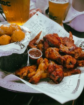 Savor spicy chicken wings with a dipping sauce, paired with beer in a cozy Bucaramanga bar.