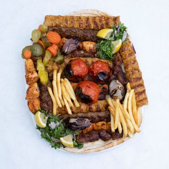 A mouth-watering grilled platter featuring kebabs, grilled vegetables, and fries, perfect for a feast.