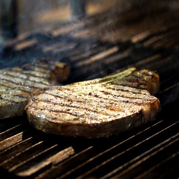 Close-up of sizzling steaks with grill marks on a barbecue grill, highlighting delicious cooking.